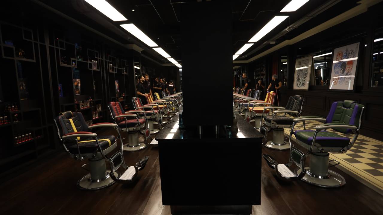 Sala escura com fileiras de cadeiras de barbearia