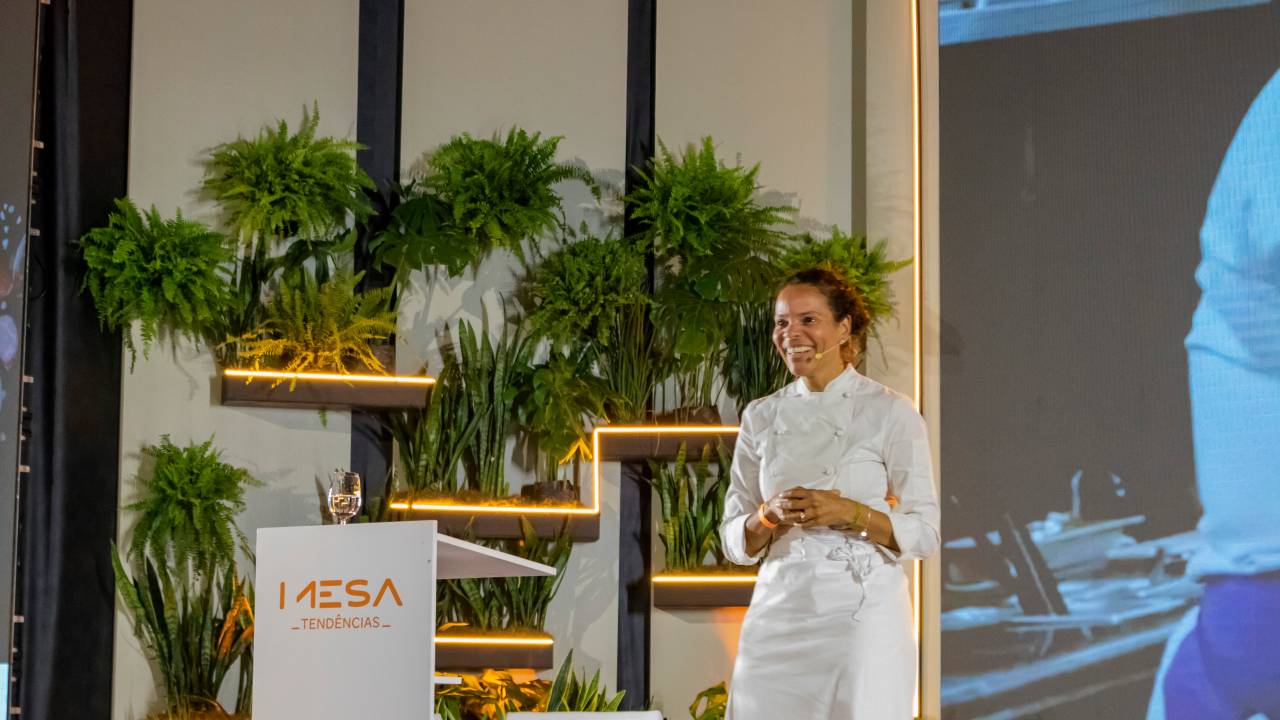 A chef Alessandra Montagne em um palco proferindo palestra