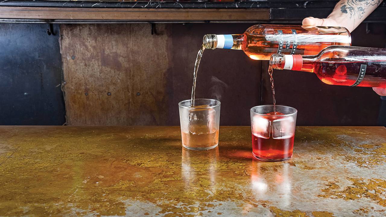 Dois copos com bebidas sendo colocadas