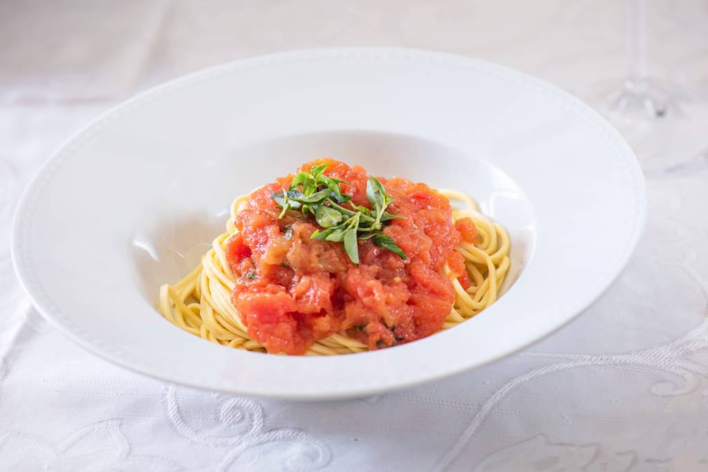 Trenette ao molho de tomate com manjericão – Santo Colomba Prato branco com macarrão e molho