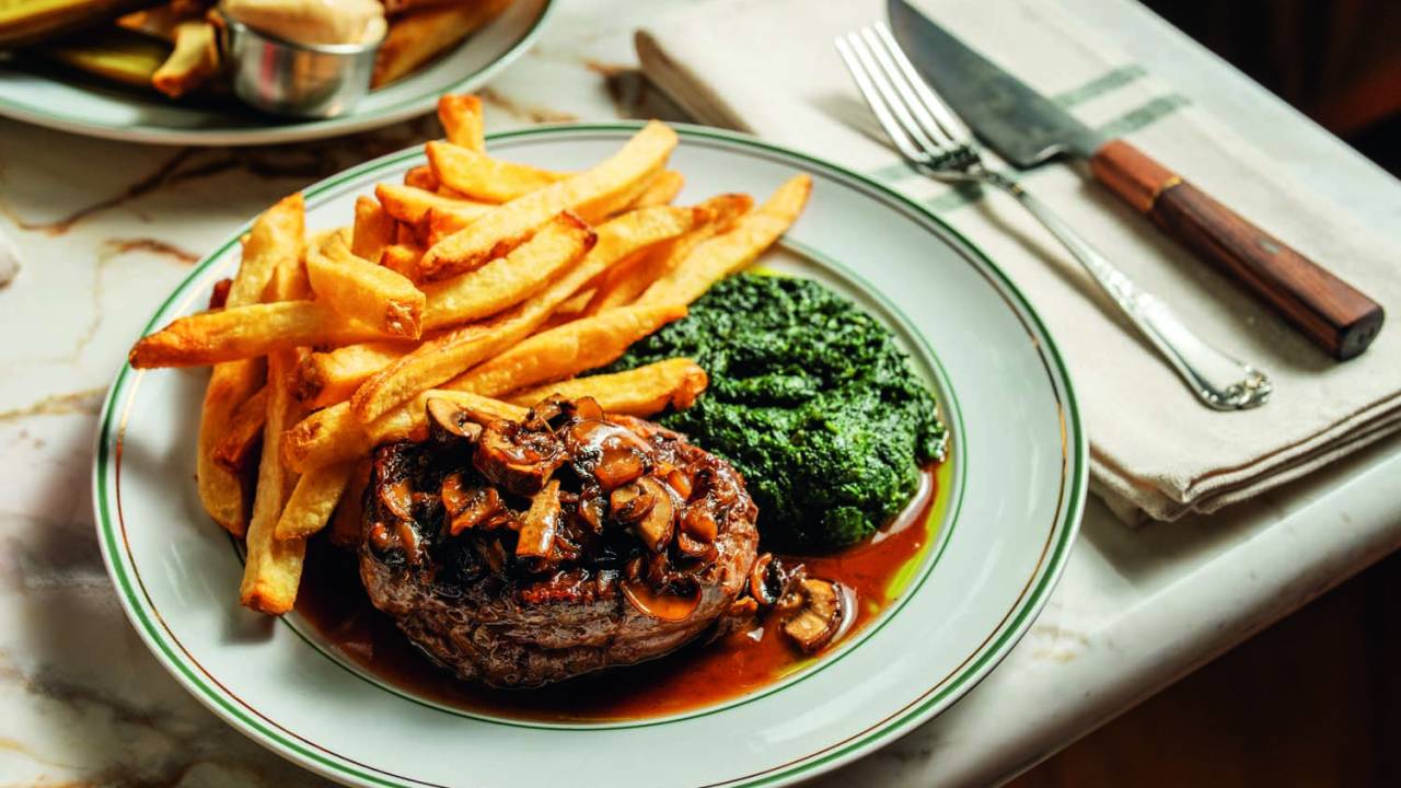 Prato branco com carne, batatas e espinafre