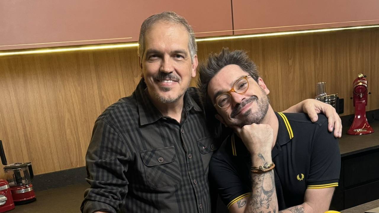 Dois homens abraçados e olhando pra câmera