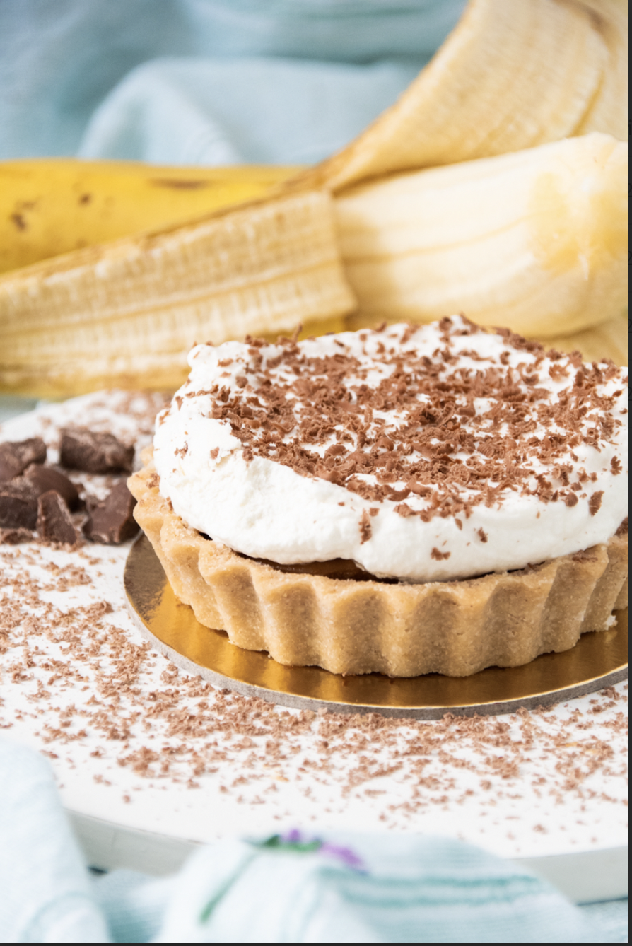 Canelle_Banoffee_Cred. Victoria Caldini (1) Torta em cima de recipiente dourado e banana atrás