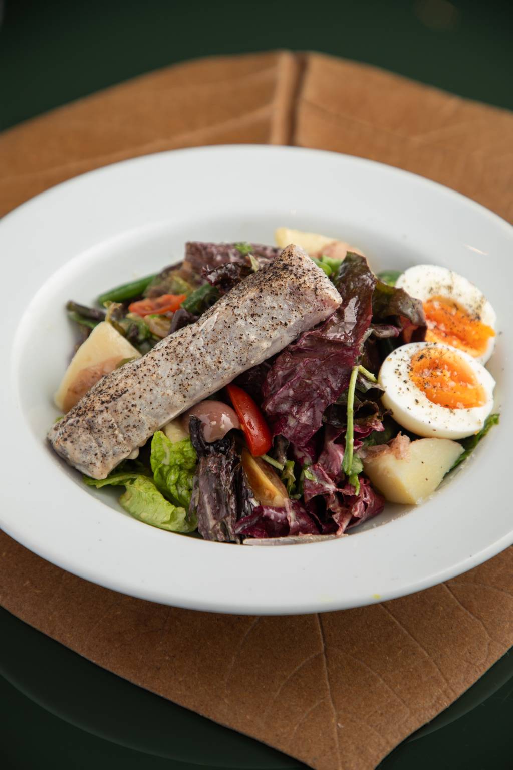 Salada niçoise tomate , azeite e limão _ Charlô Prato branco com salada e ovos