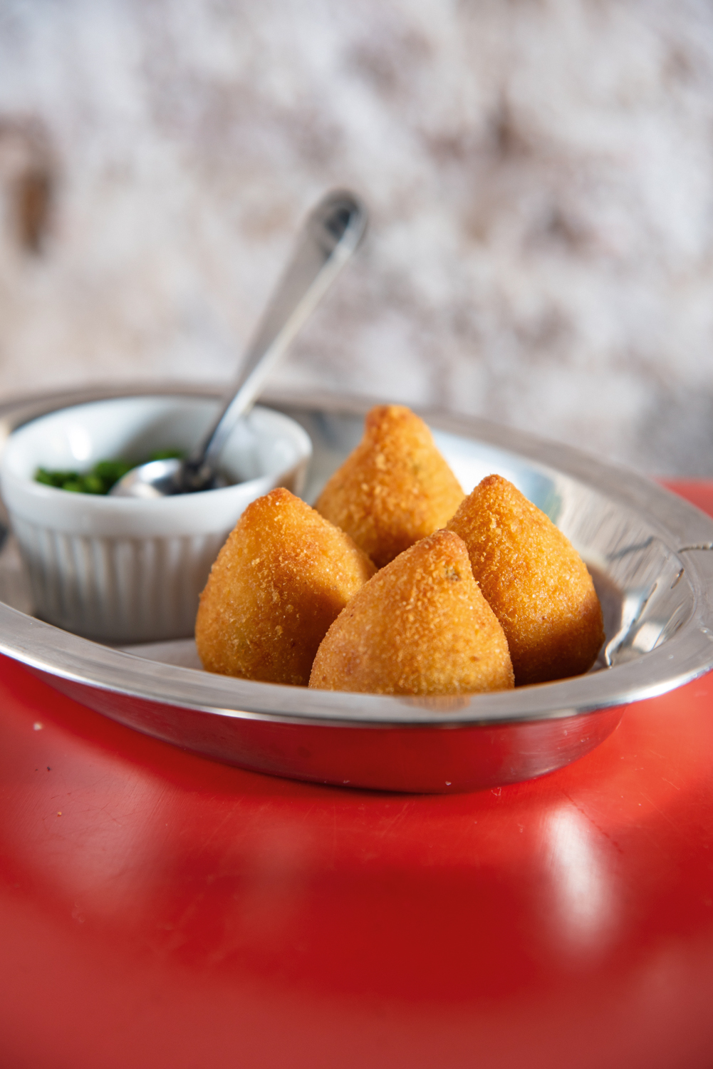 Boteco de Manu Coxinhas em prato de metal e molho