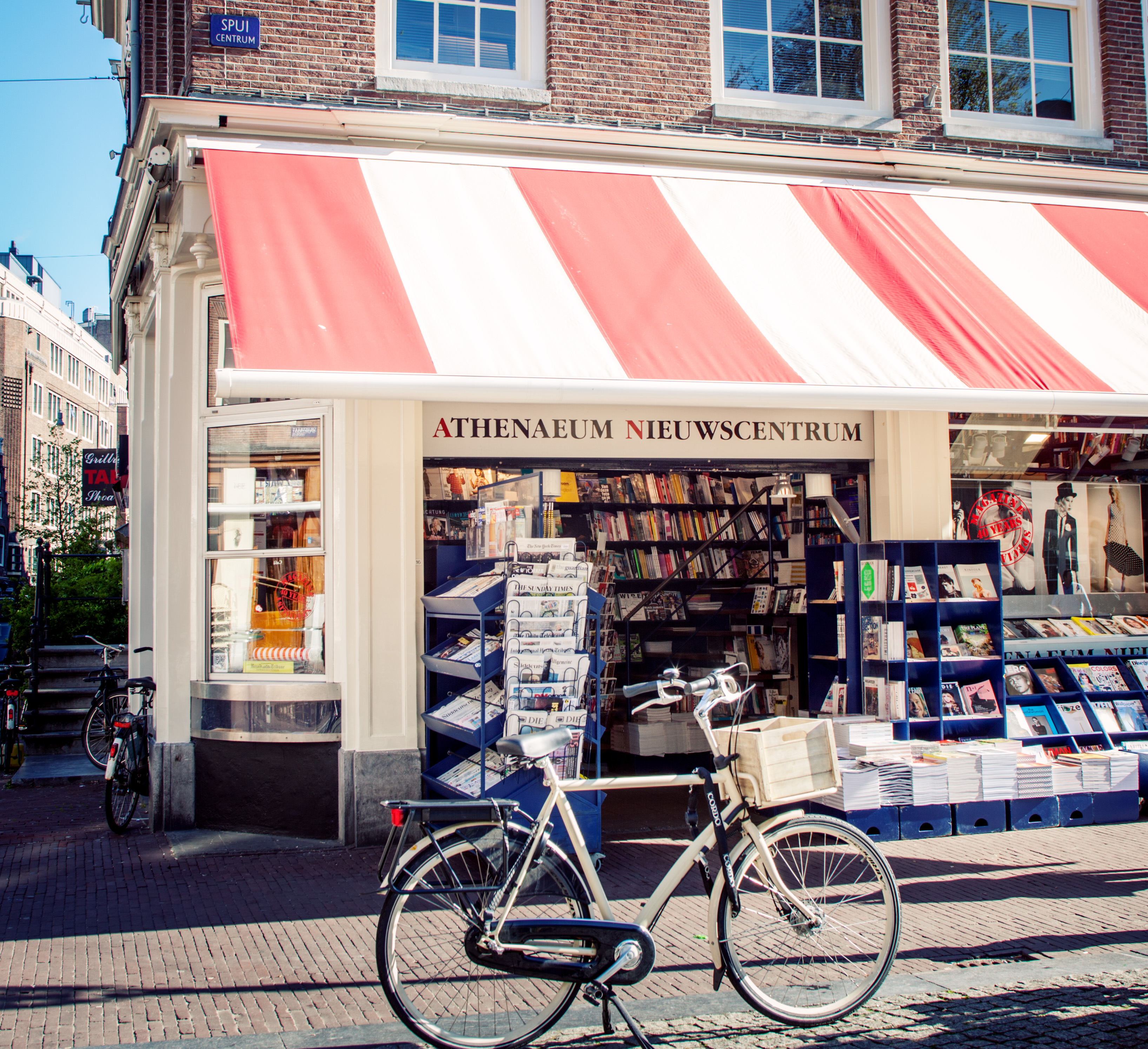Foto de livraria com bike na porta e toldo listrado em branco e vermelho