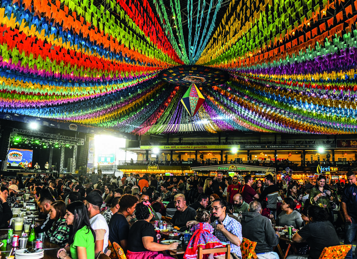 Bandeiras coloridas no teto e pessoas sentadas embaixo