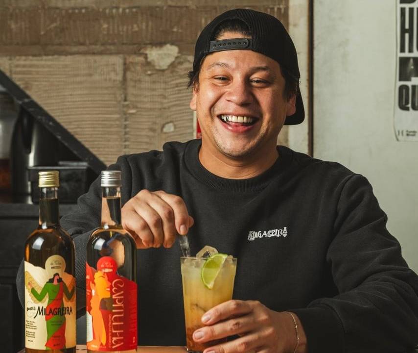 Homem sorrindo e preparando drinque