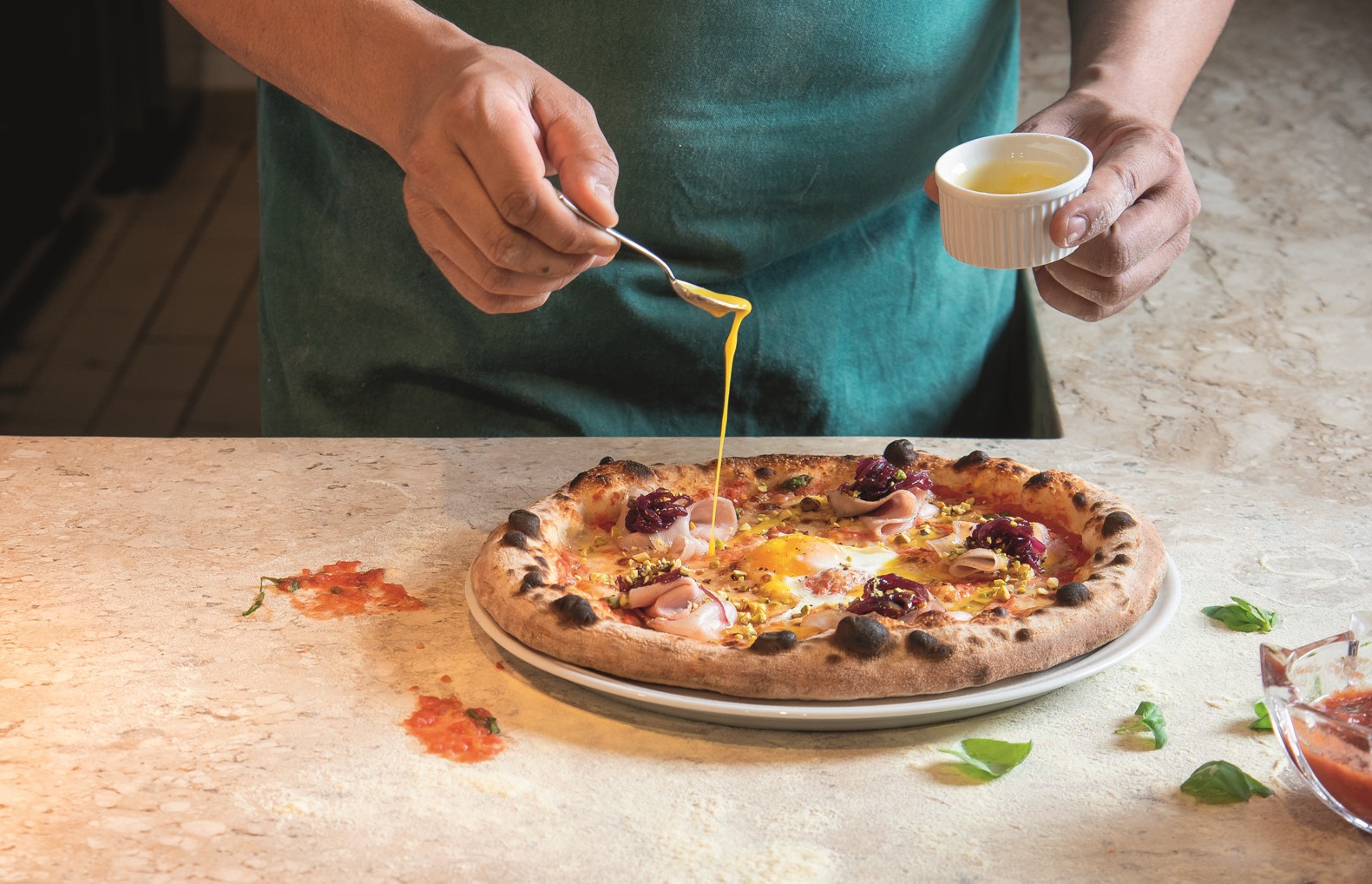 Pizza sendo finalizada em mesa de madeira