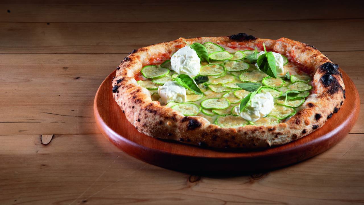 Disco de pizza em cima de prato e mesa de madeira